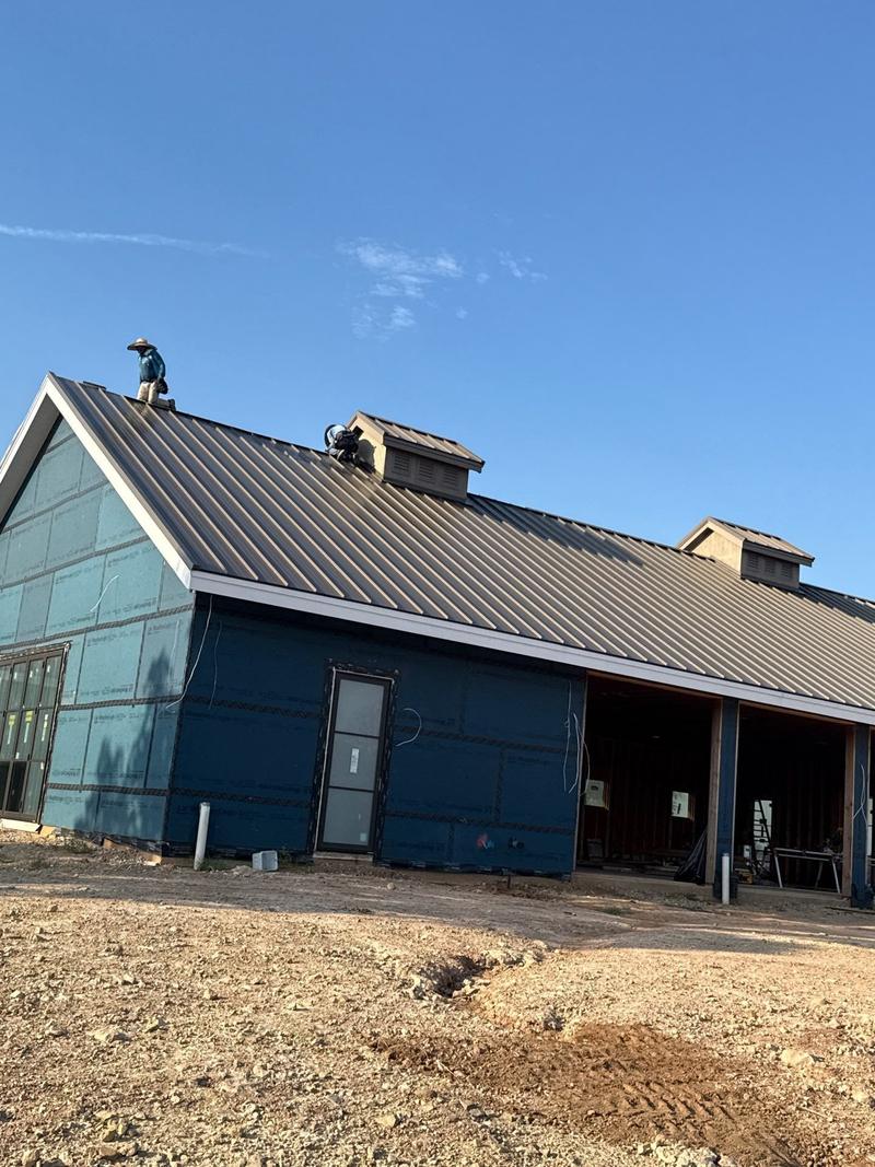 Standing seam metal roof on a blue board-and-batten wing of a ranch estate