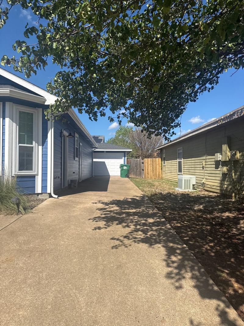 Driveway-side view of a home with new siding painted blue and white trim