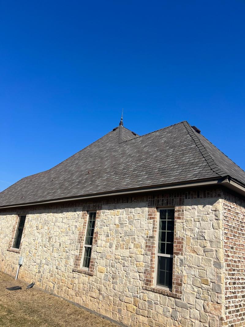 Side elevation of a stone home with a new slate-look shingle roof