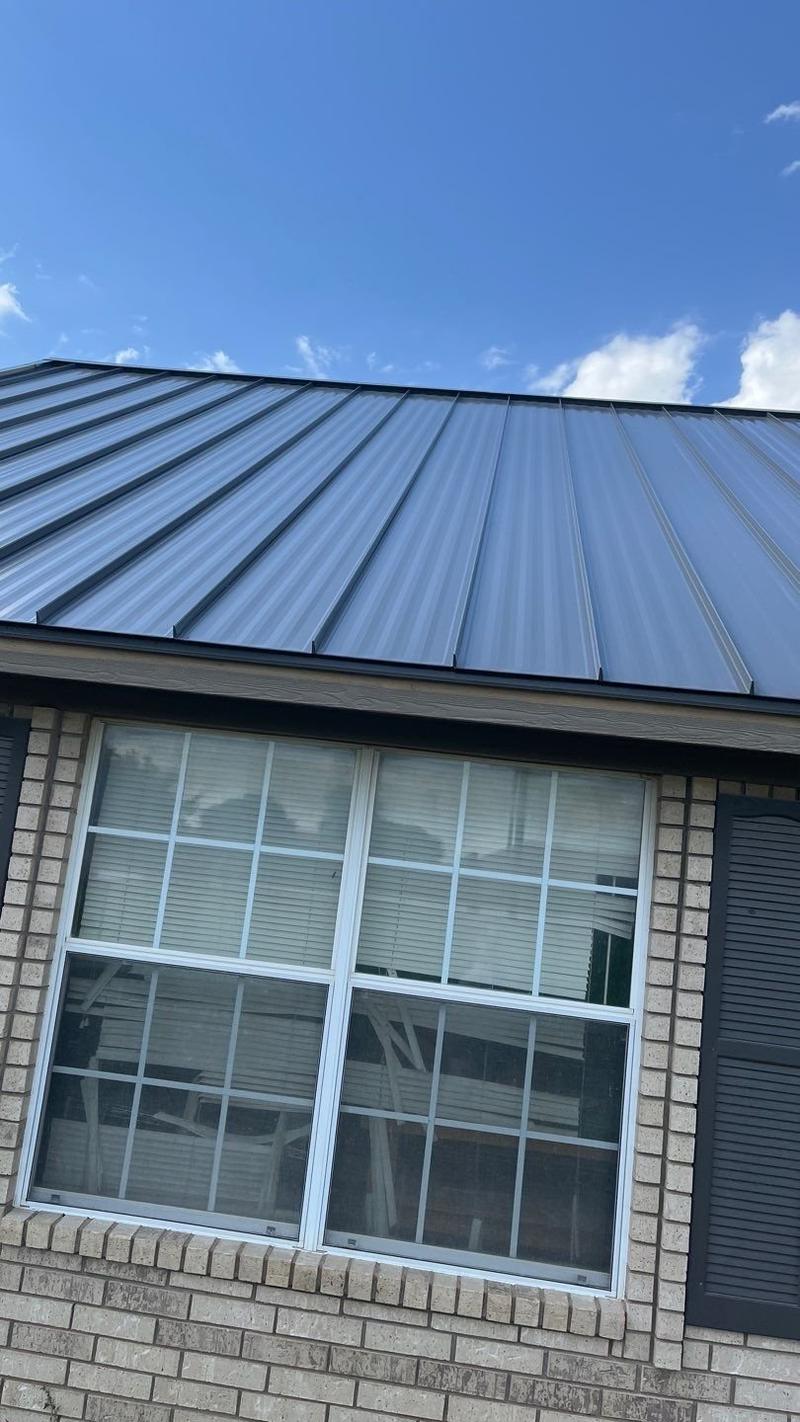 Close view of standing seam panels at the eave of a brick ranch home