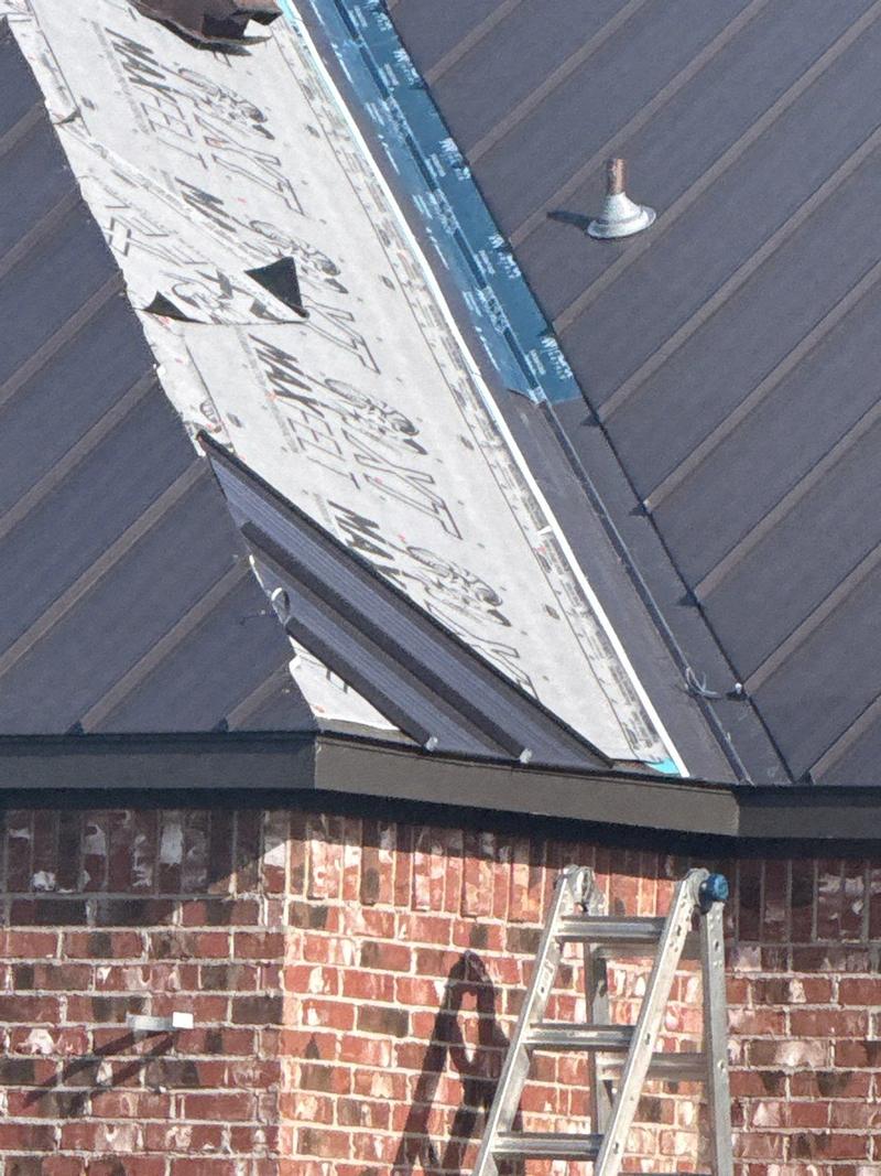 Standing seam panels going on over synthetic underlayment at a hip